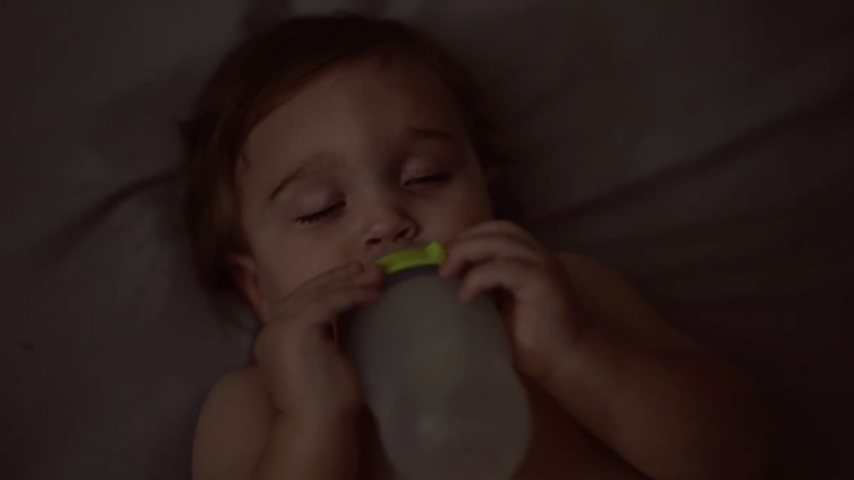Baby drinking from a bottle in low light