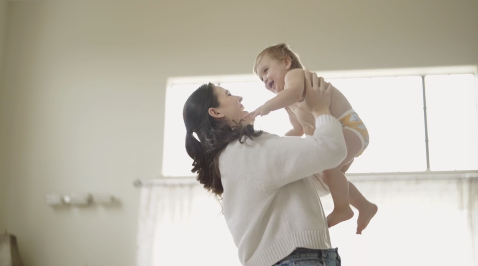 Woman lifting a laughing baby toward the window