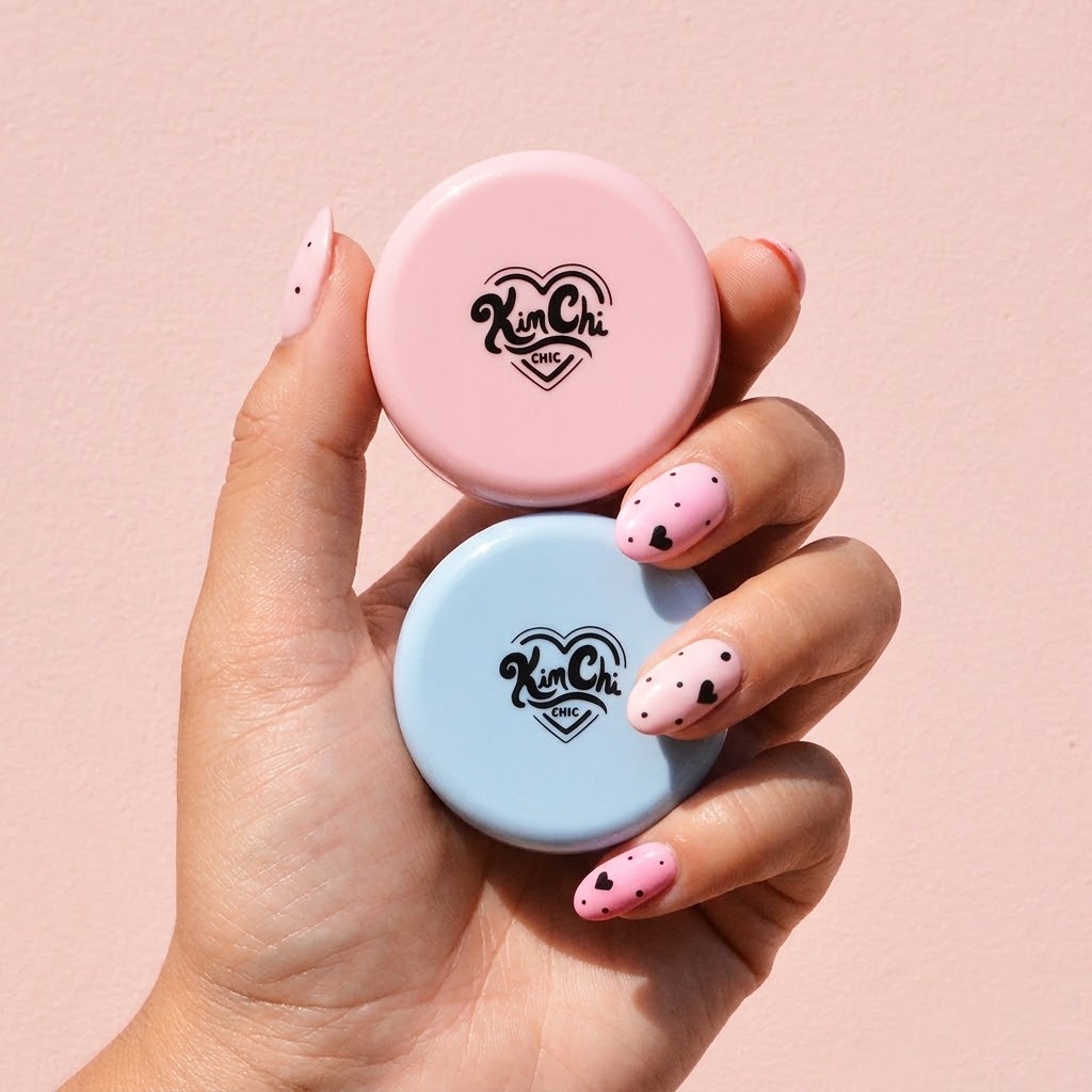 Hand holding pink and blue lip balm tins