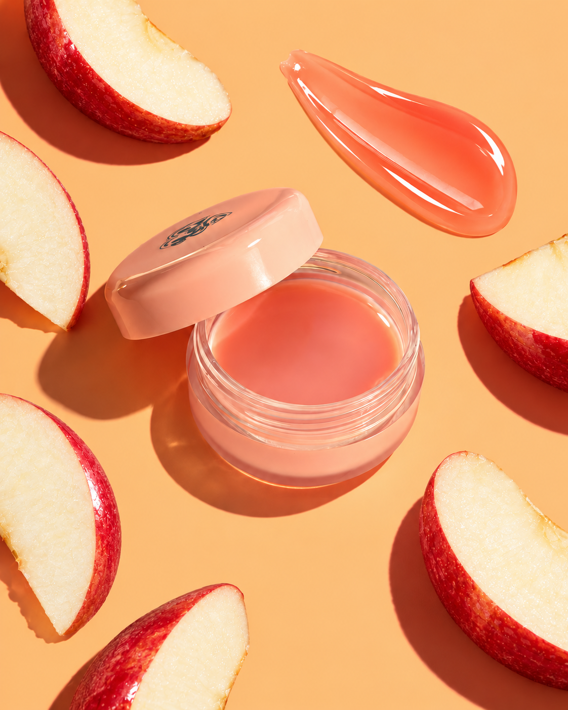 Open coral lip balm with texture swatch and apple slices